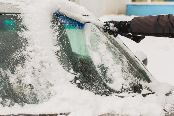 用刷子清理汽车上的积雪。雪下的汽车。冬天的天气。气候。风暴。运输图片下载