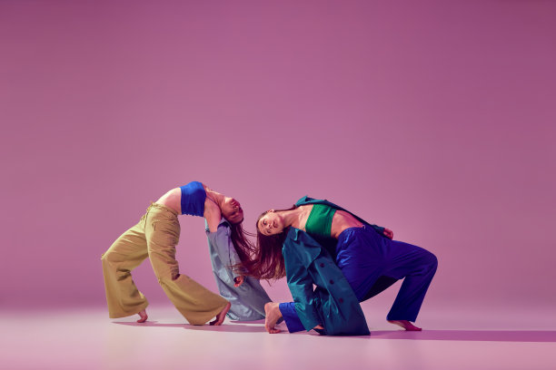 活力四射的舞者在舞厅进行艺术表演。年轻时髦的时尚女孩跳舞孤立的水晶粉红色的背景。艺术，时尚，风格图片下载