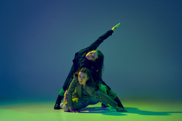 奇怪。在霓虹灯下的舞厅里，时髦的年轻女孩穿着休闲装，在渐变的蓝绿色背景上跳着实验性的舞蹈。青年文化图片下载