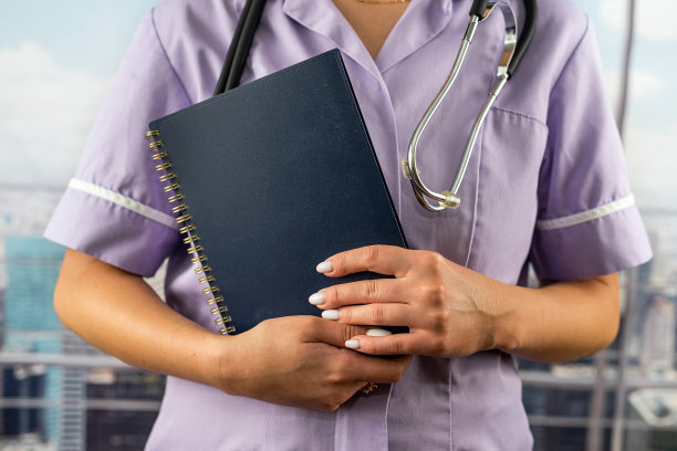 不认识的实习生穿着制服，带着听诊器阅读医学书籍的剪影图片下载