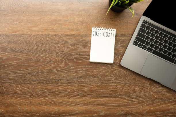 白板笔记本放在木质办公桌上，桌上有笔记本电脑。顶视图与复制空间，平铺。图片下载