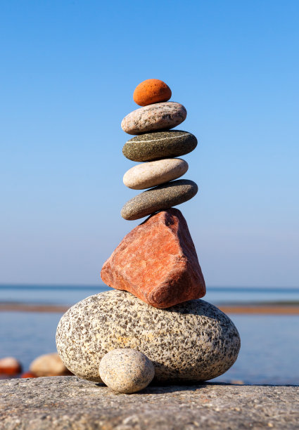 岩石禅宗金字塔的不同形状的石头在蓝天和大海的背景。图片下载