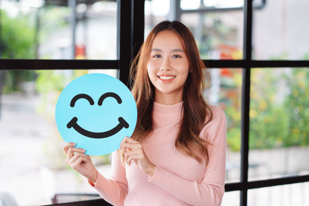 亚洲妇女在剪纸上抱着蓝色快乐的笑脸，用户给予良好的反馈评级，积极思考，客户评审，评估，心理健康日，赞美日，满意的概念。图片下载