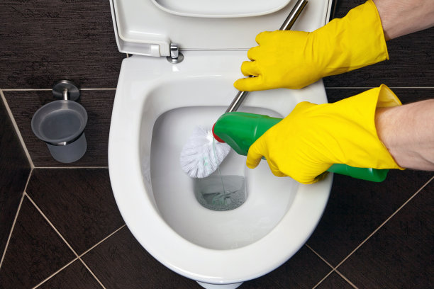 戴着黄色橡胶手套的清洁工用刷子和消毒剂清洁抽水马桶图片下载