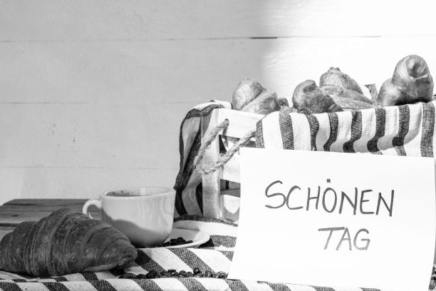 美味的新鲜糕点牛角包，咖啡和纸的灰度照片，文字“美好的一天”图片下载