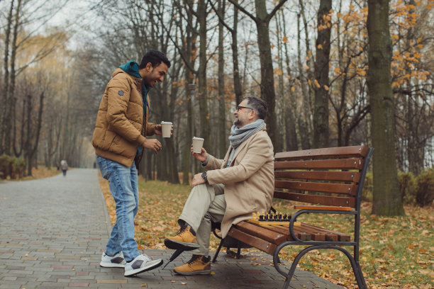 不同年龄的人的多元文化友谊。两个朋友在公园里下棋。图片下载