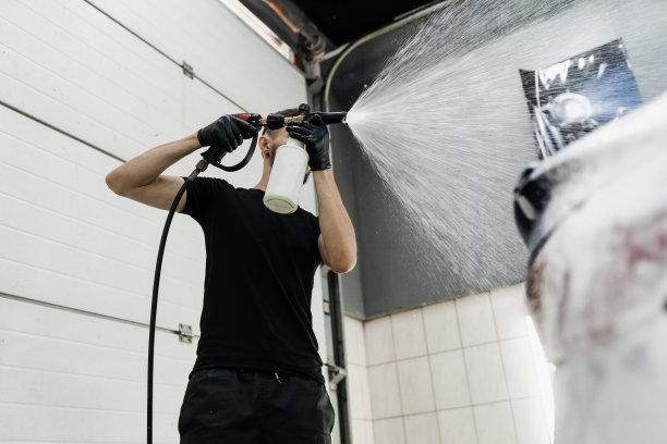第二阶段的详细洗车服务。洗车工做全身洗车。在车库向车身喷洒泡沫的过程。图片下载
