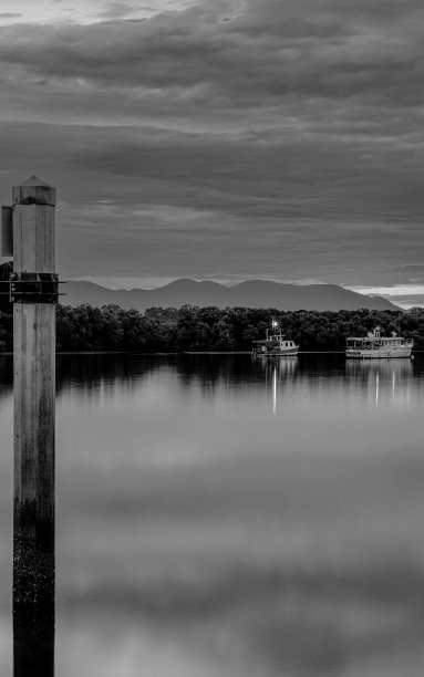 垂直的黑白照片，湖面上有船和云的倒影图片下载