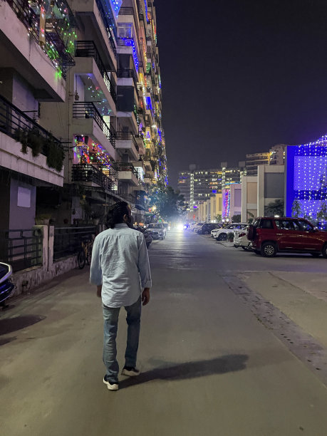 在印度传统灯节排灯节上，印度德里，一个面目全非的人走过高层公寓大楼图片下载