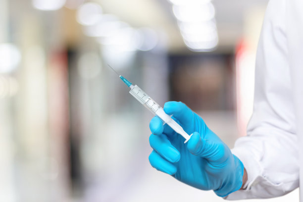 一只戴着手套拿着注射器的手。图片下载