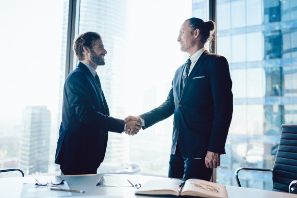 愉快的男同事穿着正式优雅的西装，对在办公室会面后达成业务合作协议感到满意，男经理打着手势握手，友好交谈图片下载