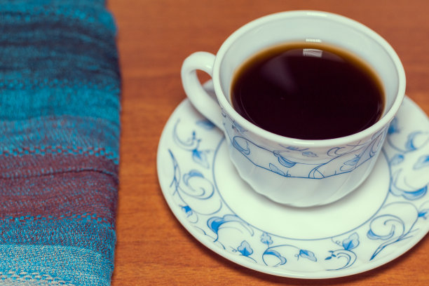 一杯茶，旁边是一张蓝色的桌布，放在木桌上图片下载