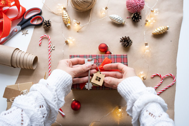 钥匙的房子与钥匙链在舒适的家与圣诞装饰包装礼品盒。为新年、圣诞节打包礼物。建筑，工程，搬迁到新房子，抵押，租赁，购买房地产图片下载