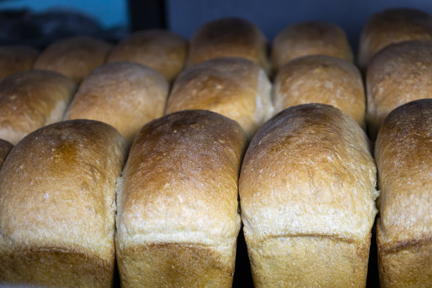 刚煮熟的热面包放在面包房里的托盘里。图片下载