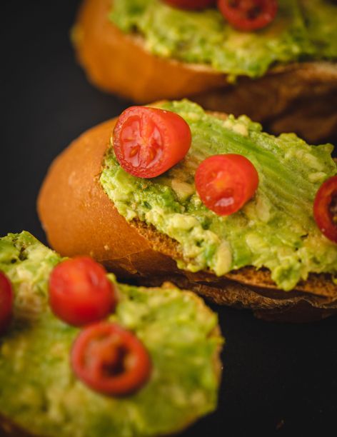垂直特写鳄梨吐司与樱桃番茄在黑色表面图片下载
