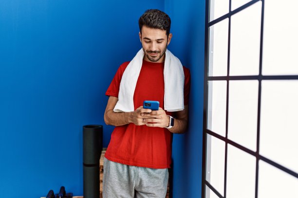 年轻的西班牙人穿着运动服在运动中心使用智能手机图片下载
