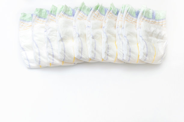 婴儿的东西纸尿裤躺在一排白色背景与复制空间。新生儿，婴儿，婴儿送礼，保健医疗理念图片下载