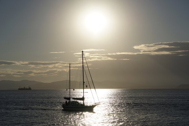 日落时的游艇。海参崴美丽的日落。日本海海滩上的日落。游艇在日落时在海上航行。海上日落，高山和游艇。图片下载