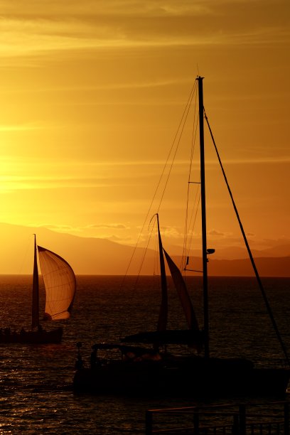 日落时的游艇。海参崴美丽的日落。日本海海滩上的日落。游艇在日落时在海上航行。海上日落，高山和游艇。图片下载