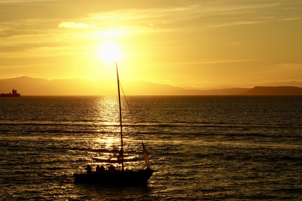 日落时的游艇。海参崴美丽的日落。日本海海滩上的日落。游艇在日落时在海上航行。海上日落，高山和游艇。图片下载