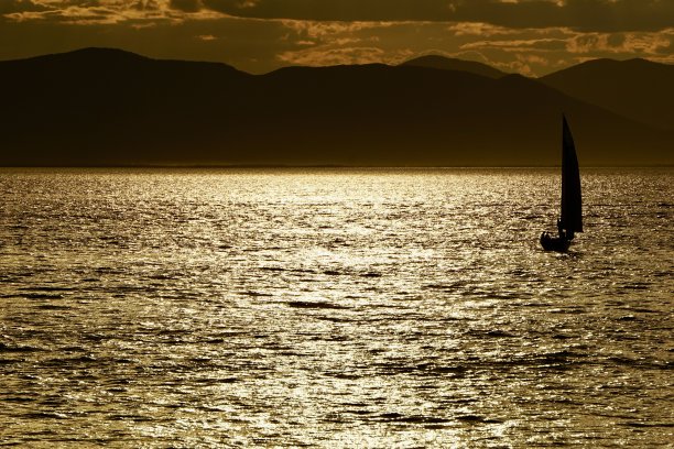 日落时的游艇。海参崴美丽的日落。日本海海滩上的日落。游艇在日落时在海上航行。海上日落，高山和游艇。图片下载