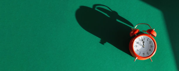 红色闹钟与叠加阴影隔离在绿色背景。圣诞快乐和新年快乐的节日贺卡。复制空间，俯视图，平铺。横幅图片下载