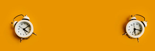 黄色背景上的白色闹钟。文本的空白。图片下载