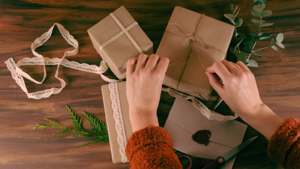 妇女手结黄麻丝带在一个木制背景的牛皮纸礼物图片下载