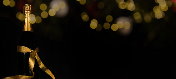 新年快乐2023节日庆祝节日新年前夜的贺卡背景-香槟或起泡的酒瓶与金色的礼物丝带和散焦灯在黑暗的夜空图片下载