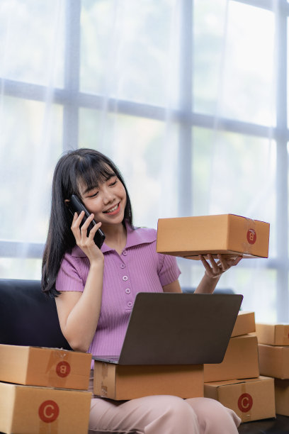 小型企业初创企业中小企业所有者亚洲女性企业家使用笔记本电脑接受和检查网上订单，为中小企业客户网上商业想法准备销售包装盒。垂直图图片下载