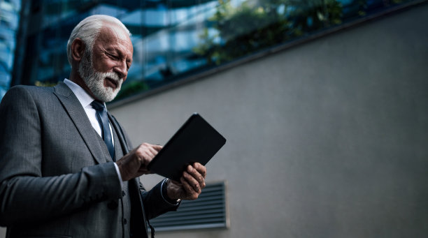 自信的商人分析关于电子平板电脑和办公楼的想法。图片下载