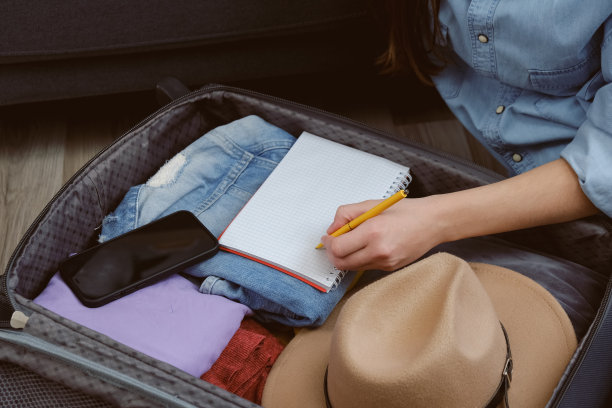 近距离旅客年轻女子坐在温暖的地板上检查东西之前，去旅行或假期。探险者女孩小心翼翼地把行李箱装在家里的个人物品。旅行生活方式概念图片下载