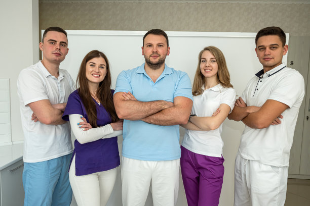 年轻漂亮、穿着体面的牙医漂亮地站在他们的牙科诊所里。图片下载