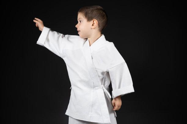 一个穿着和服的小男孩把手指向黑色背景的一侧。图片下载