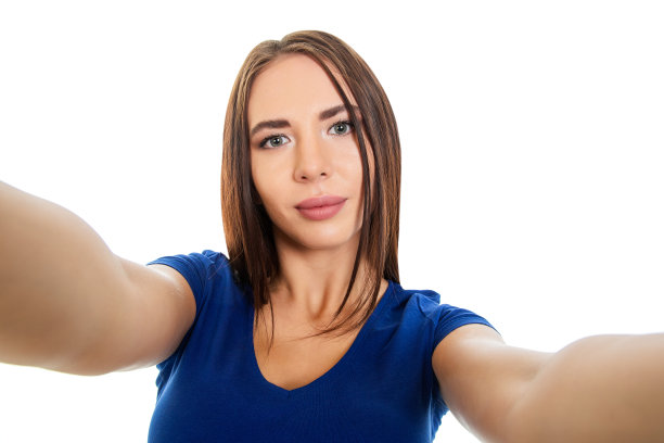 一个美丽的女孩在自拍，双手拿着相机放在一边。图片下载