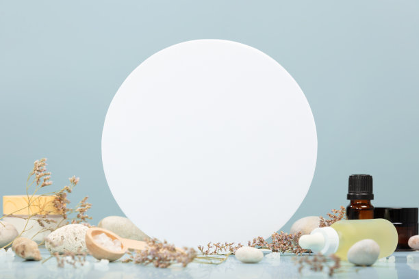 组合瓶精油，面部精华液，面霜在桌子上，石头和花朵在蓝色的背景。天然的化妆品图片下载