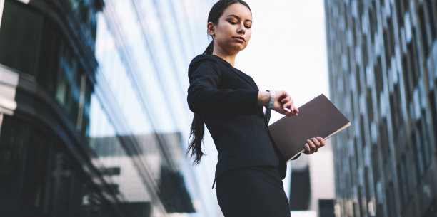 优雅的女商人在市中心看手表图片下载
