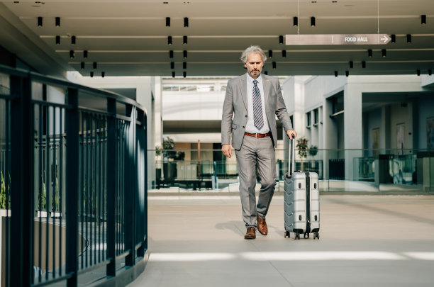 认真成熟的商人带着行李走在机场图片下载