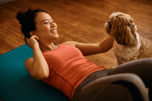 快乐的亚洲运动女性与她的狗在家里锻炼时玩得很开心。图片下载