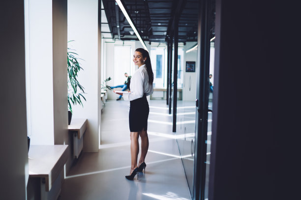 完整长度的肖像，快乐的女企业家穿着正式的服装与电子触摸板站在办公室走廊和微笑的镜头，成功的行政女性在公司摆姿势图片下载