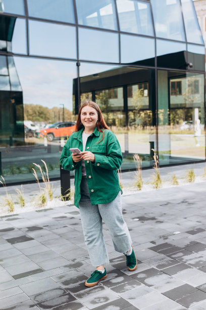 年轻的女商人在城里使用智能手机。美女在去办公室的路上用智能手机在网上搜索信息。创业，教育理念。全身照片图片下载
