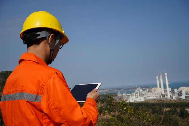 工程师用平板电脑规划工厂，同时站在高处图片下载