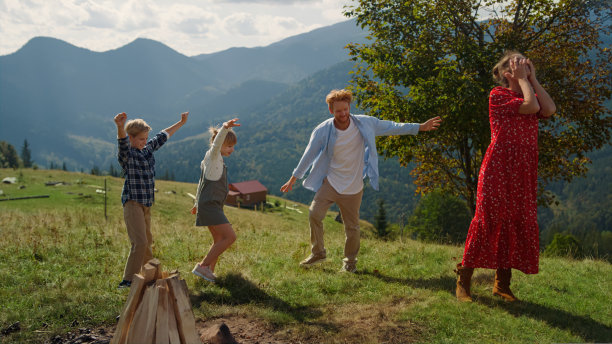 活跃的家庭在青山上玩耍跳舞。快乐的父亲和孩子们一起跳跃图片下载