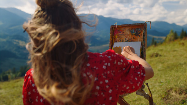 妇女创造的图片自然在山上小山特写。女孩在草地上画画。图片下载