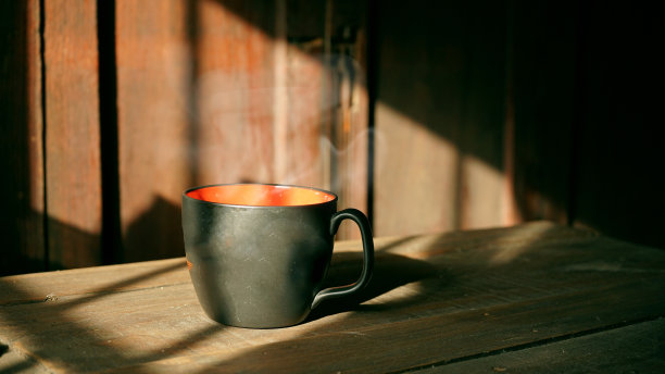 黑杯子里的热咖啡。背景是泰国老房子的阳光。图片下载