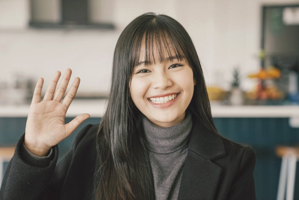 年轻的亚洲女性微笑，挥手，看着相机，远程学习，在线教学，视频会议的概念图片下载