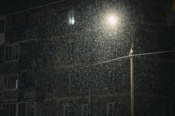 飘落的雪在黑暗的背景。雪花。冬天的天气。气候。风暴。灯笼在黑暗中发光。夜街图片下载