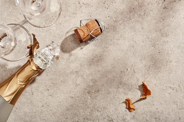 打开一瓶起泡酒或香槟和两个玻璃杯在水泥灰色表面，平躺在阳光明媚的日子与柔和的阴影图片下载