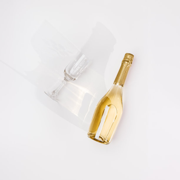 顶视图白色气泡酒瓶和眼镜葡萄酒与阳光阴影和耀斑在浅白色背景。极简的美学平铺，金色的香槟瓶。夏季酒精饮料概念图片下载