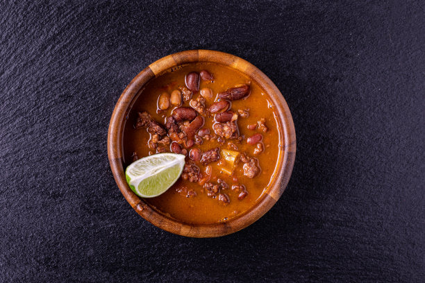 木碗辣椒配上四分之一的酸橙片在黑色的石头背景图片下载